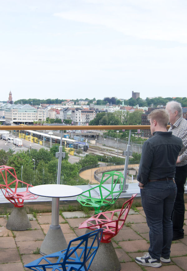 Foto som visar två personer som står på en balkong och tittar ut över Helsingborg